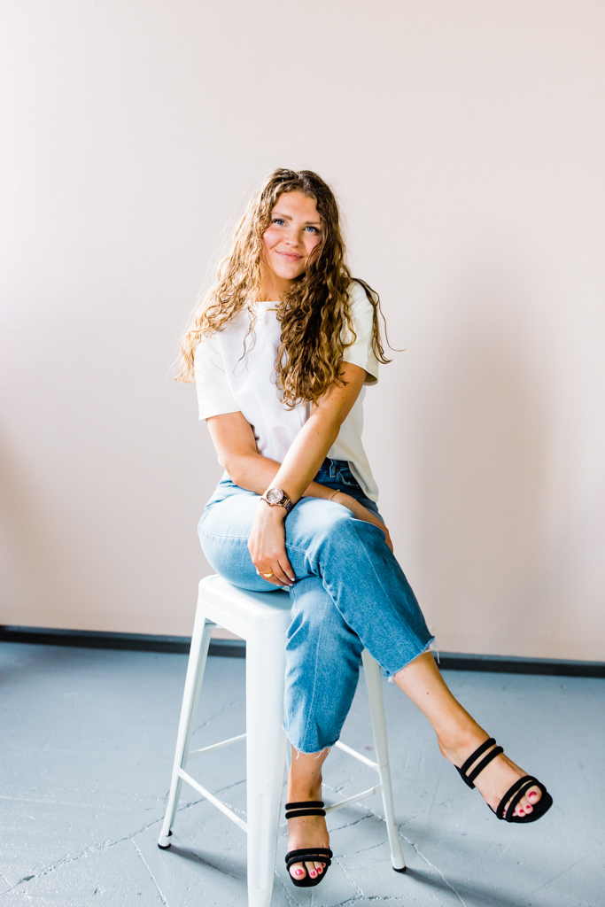 Woman sitting on stool smiles at the camera during her minnesota brand photography session