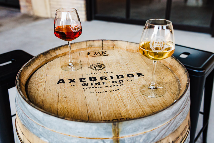 Minnesota Urban Winery Branding photos of two wine glasses on a barrel that has the words Axebridge Wine Co. on it.