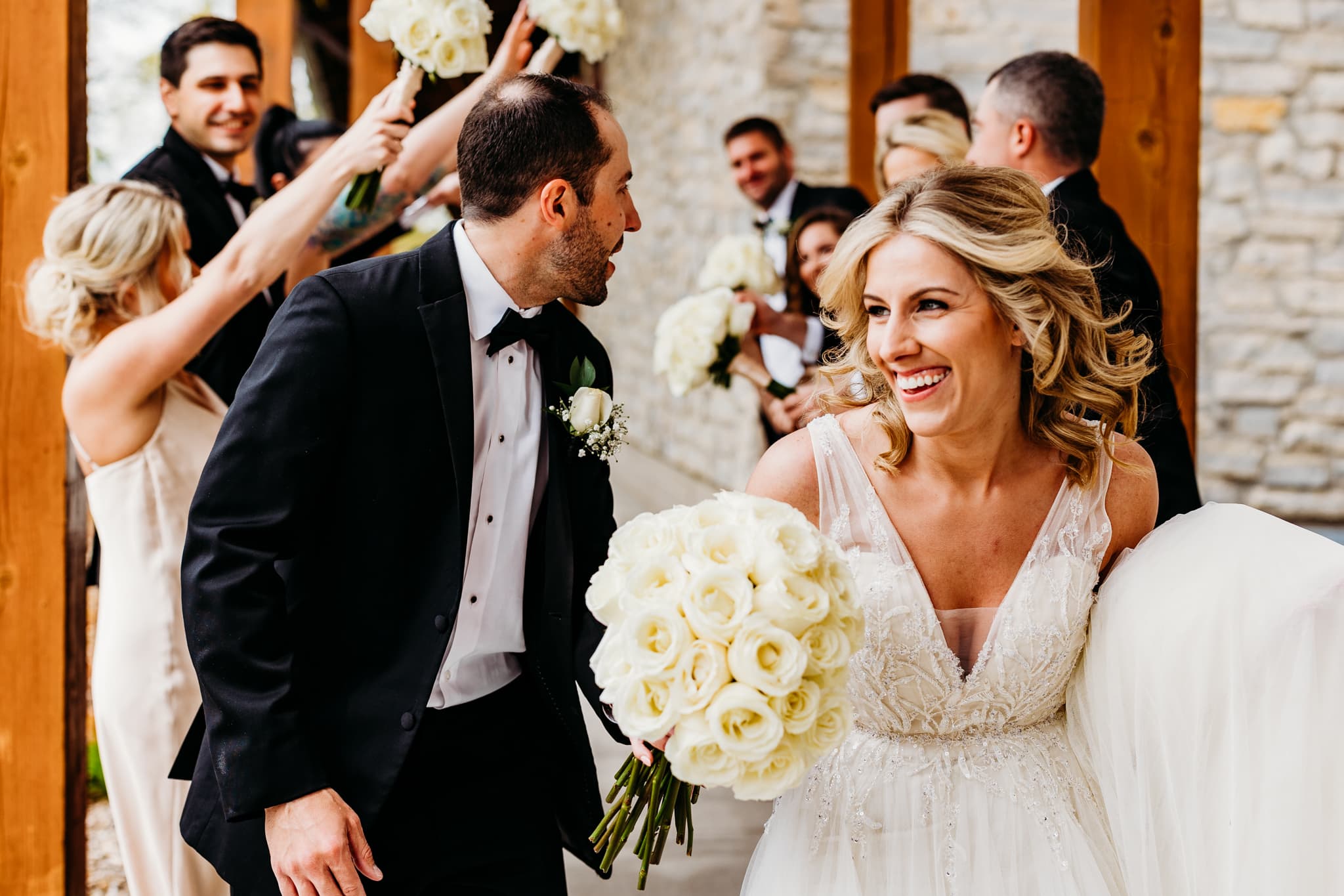 Couple runs through tunnel of wedding party's arms outside of the club house at their wedding at Hazeltine National Golf Club