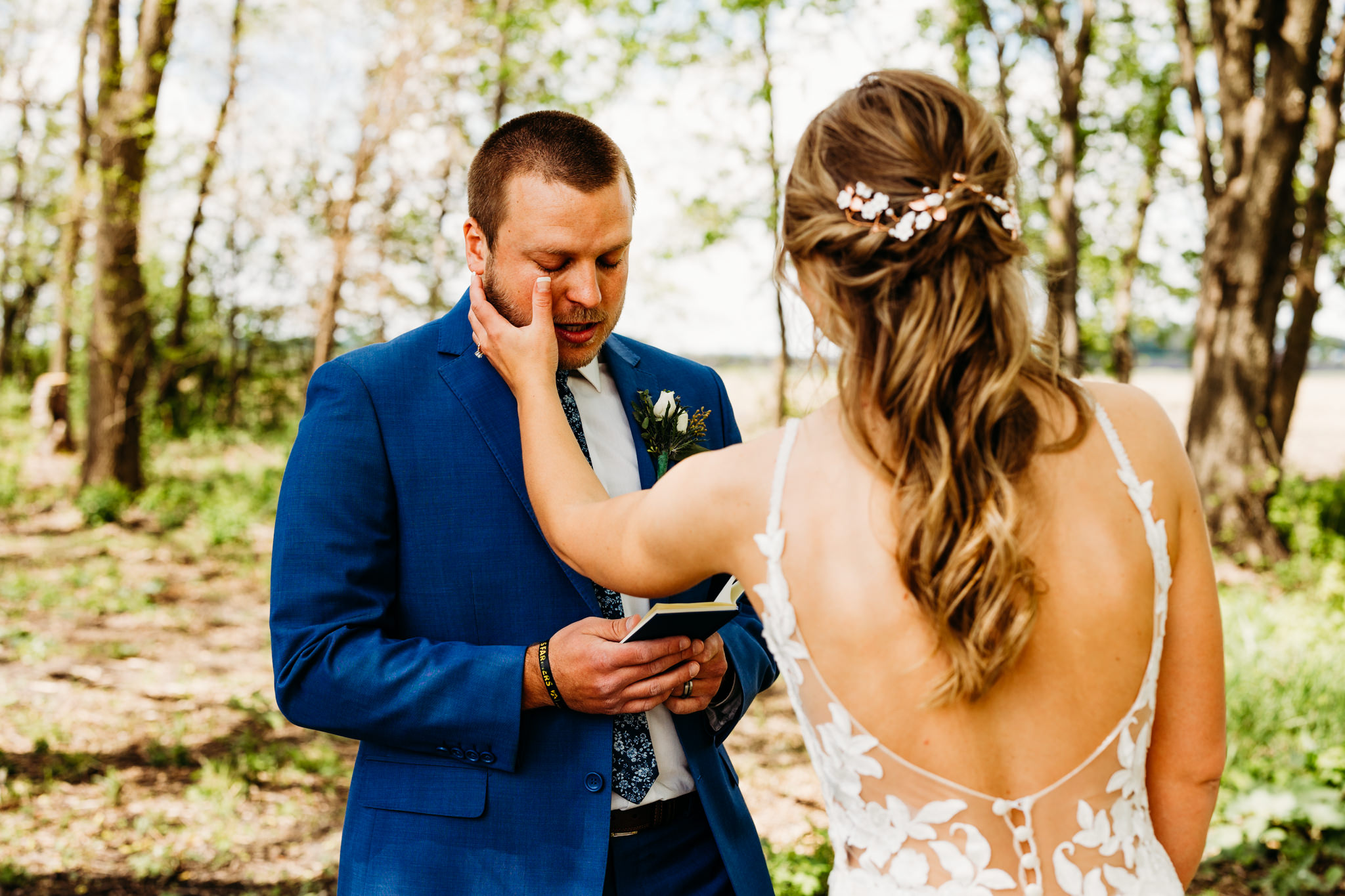 Emotional wedding photography captures bride wiping her groom's tear as he reads his vows