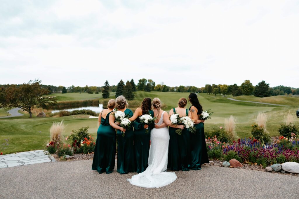 Bride and bridesmaids stand facing away from a minnesota wedding venue