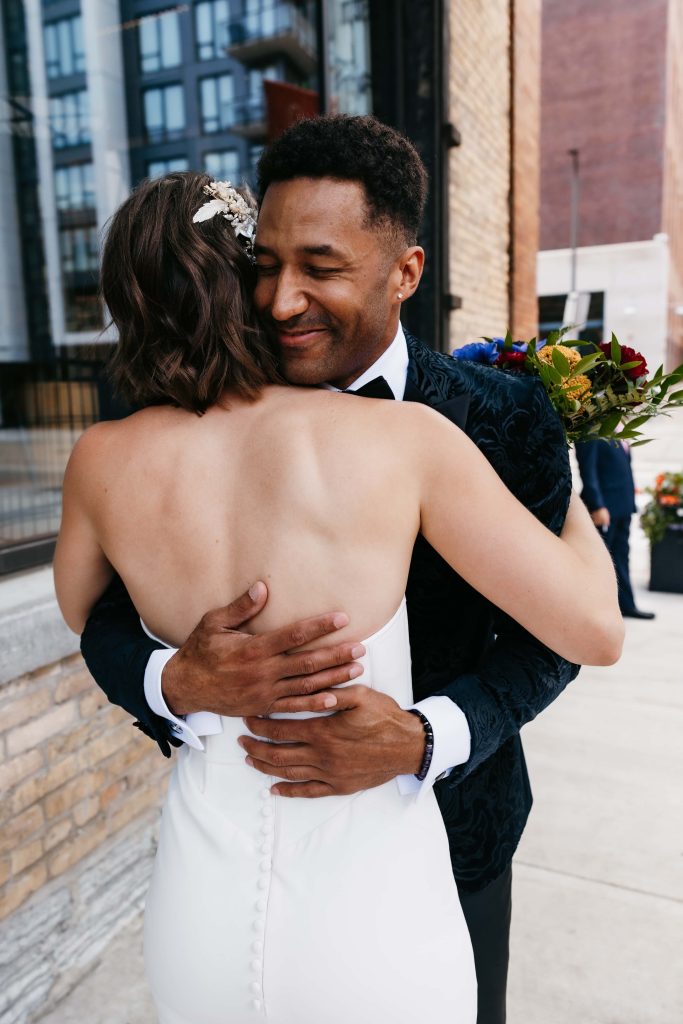 Groom hugs his bride in a white dress with short brown hair during their 10 hour wedding timeline