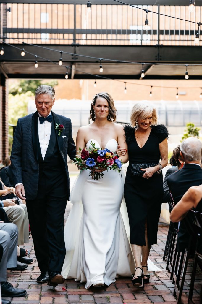 Bride is escorted down the aisle by mom and dad at her Minneapolis Event Center Wedding.