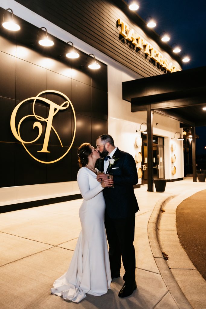 Bride and groom kiss outside of the enterance at their tattersall event center wedding 