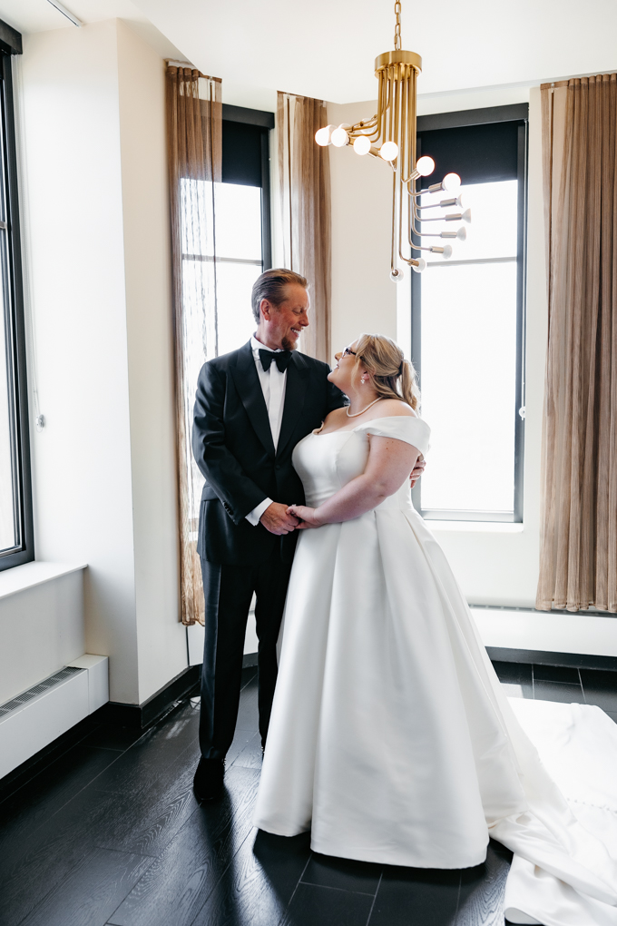 Bride in white smiles at her groom in a black suit, who learned about the average cost of wedding photography when booking for their wedding