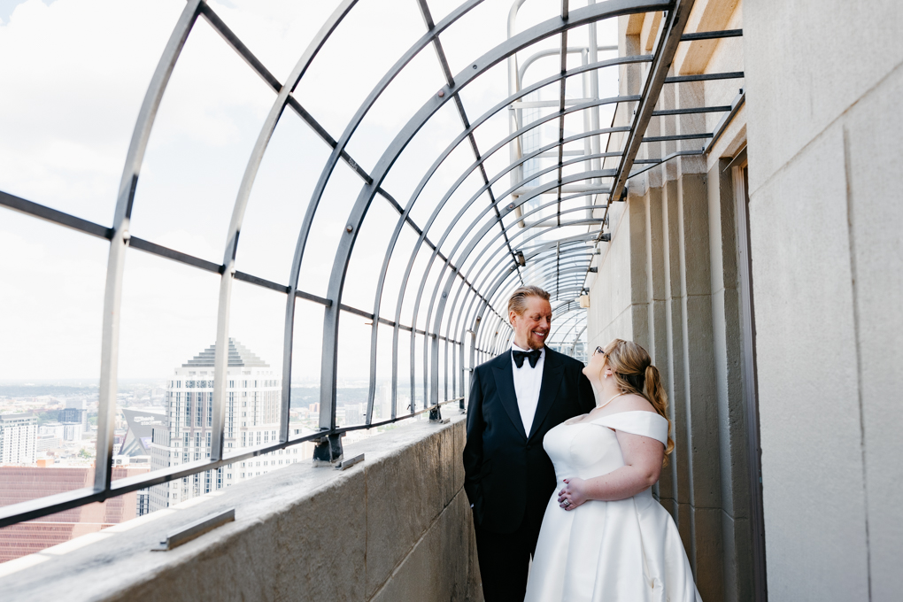 Couple smiles at least other from the observation deck at their micro wedding at Foshay Tower