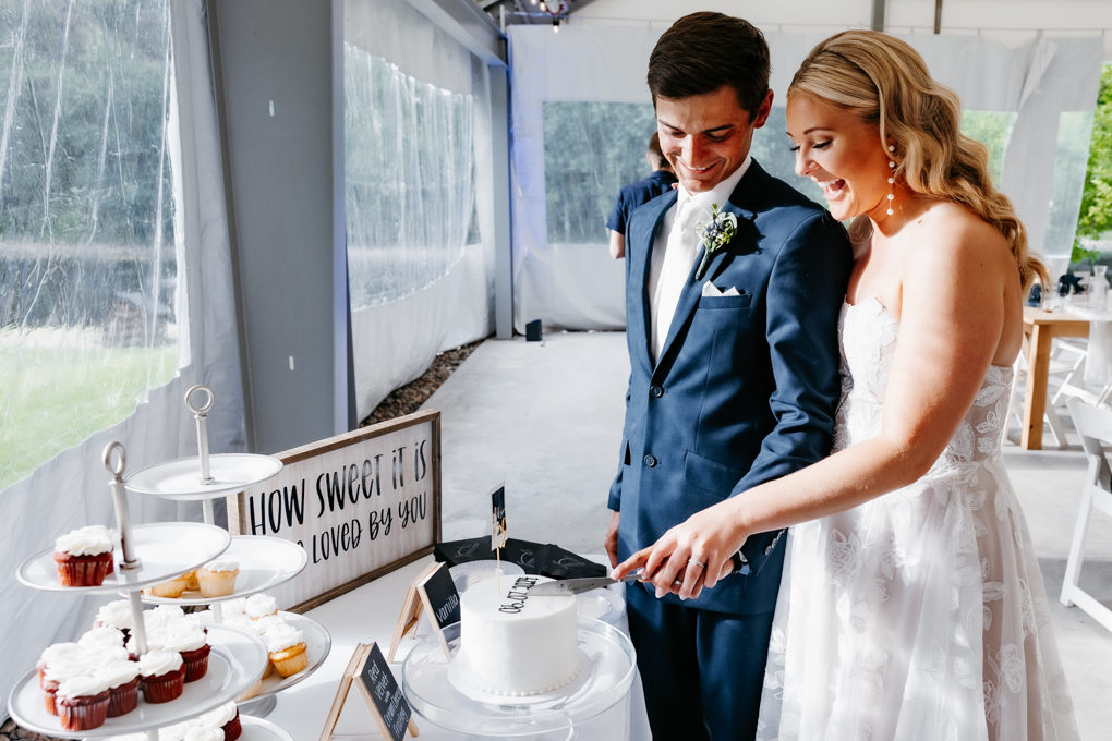 Bride and groom smile as they cut their wedding cake and their NOrthern oaks events wedding