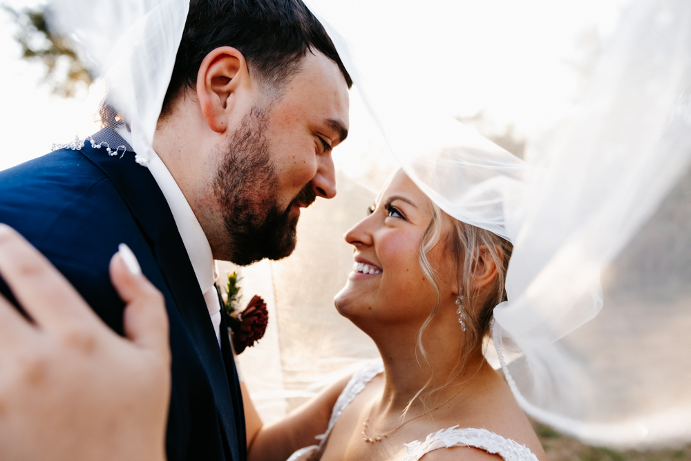 Bride and groom smile at each other under the veil