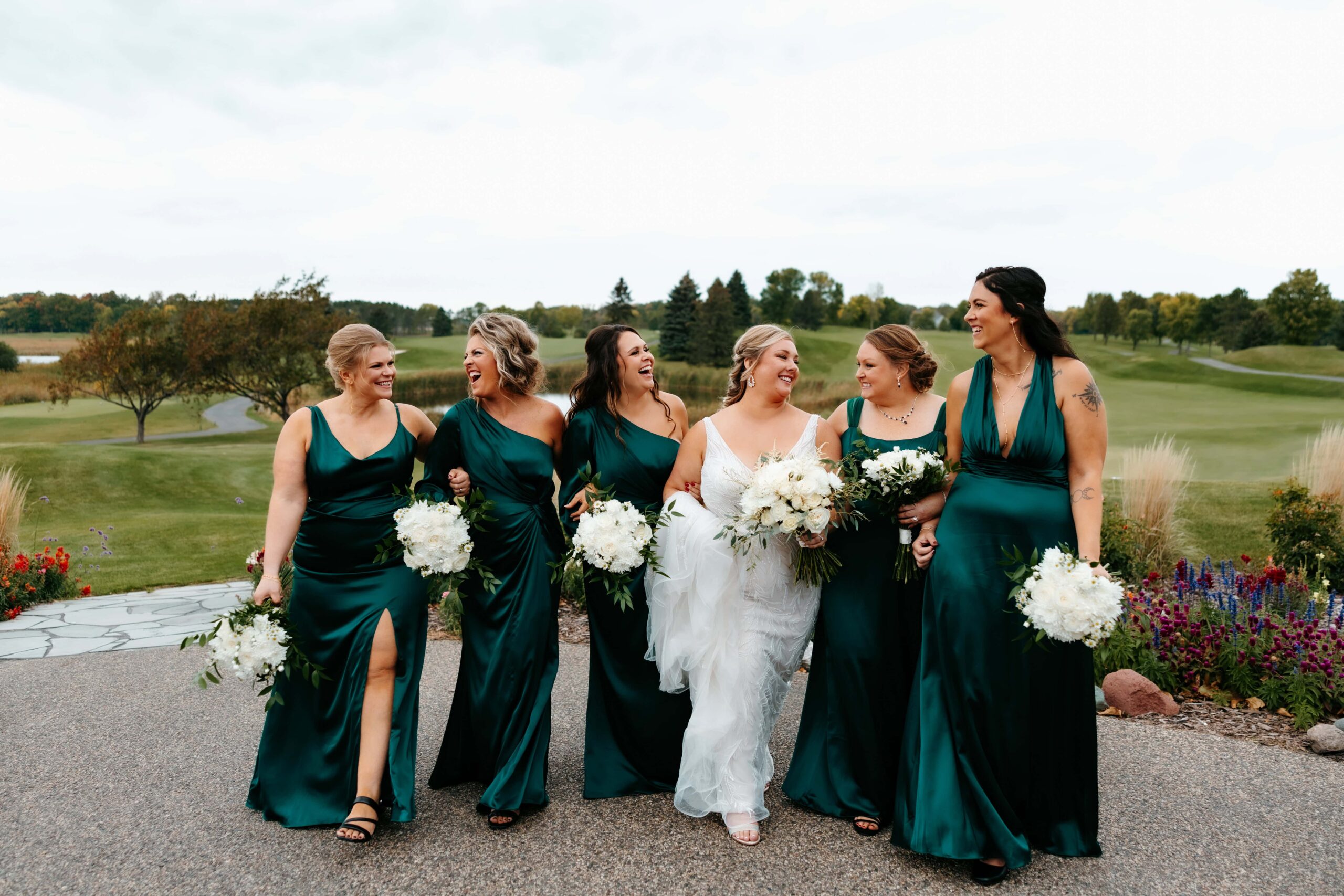 Bride laughs with her bridesmaids in green dresses at her Rush Creek Golf Club wedding