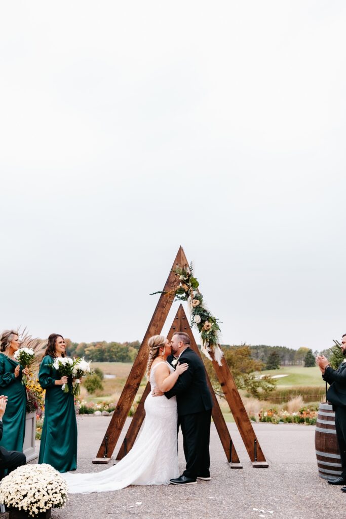 Couple kisses at the end of the aisle at rush creek golf club wedding venue