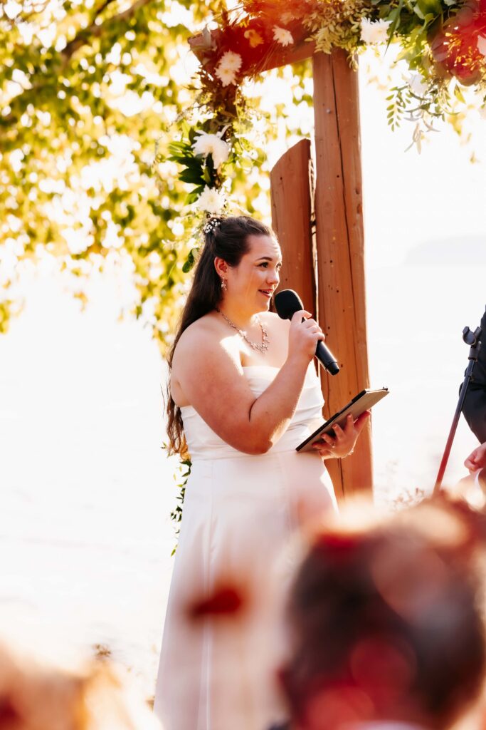 Bride in a white dress with brown hair holds and microphone at her north shore wedding