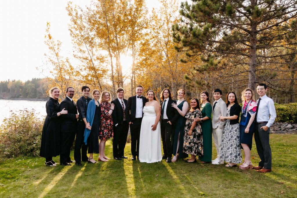 A bride and groom pose with a large group of friends at their Grand Superior Lodge wedding.